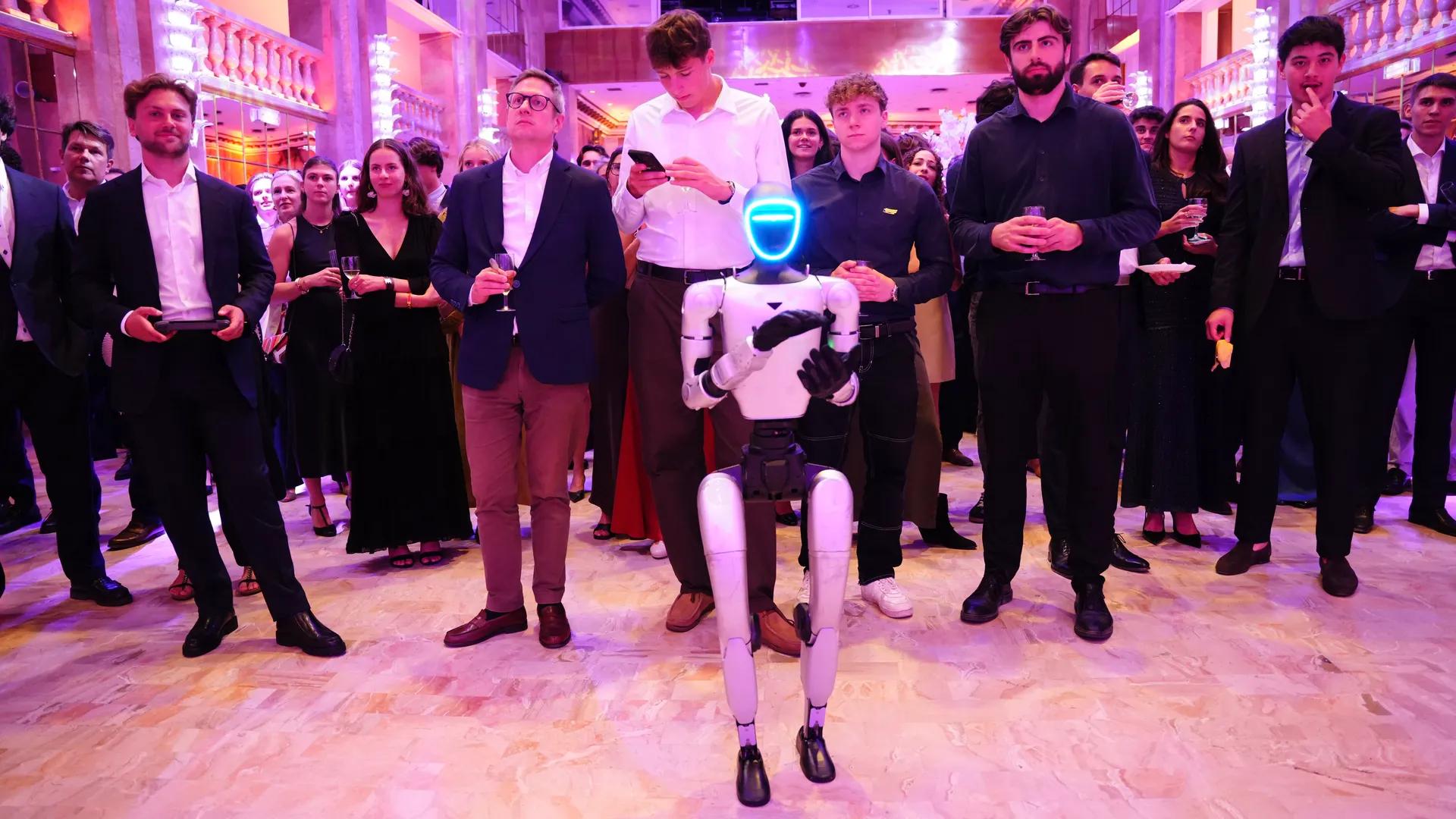 Des invités forment un cercle autour du robot humanoïde Unitree G1 lors d'un gala étudiant à Paris