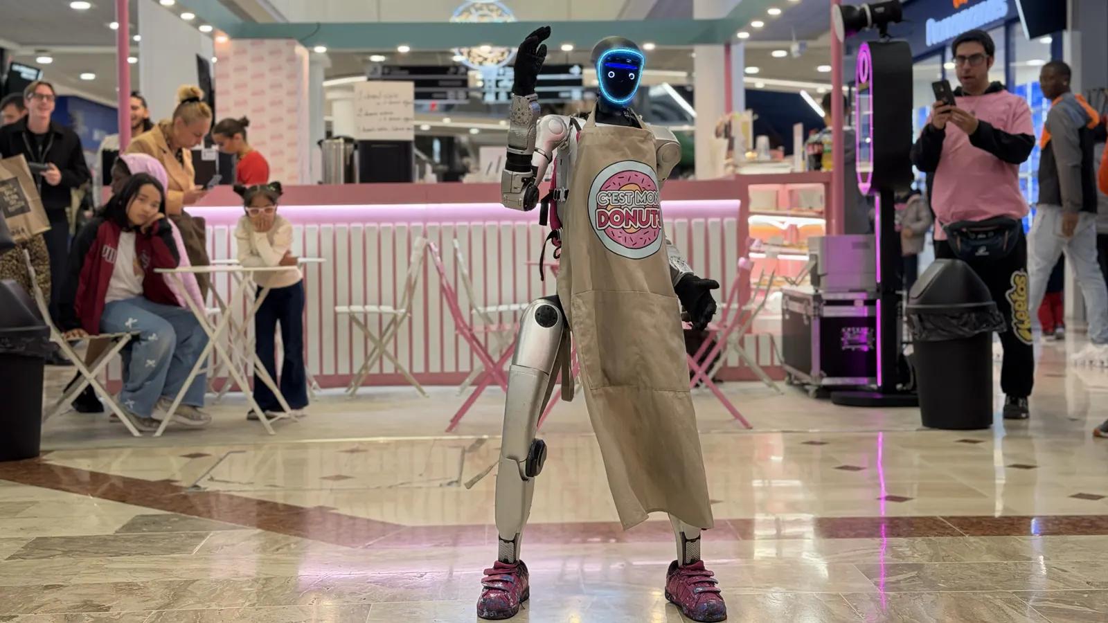 LeoBot, robot humanoïde Unitree G1 en tablier aux couleurs de C'est Mon Donuts, salue devant le stand de la marque au centre commercial Belle Épine
