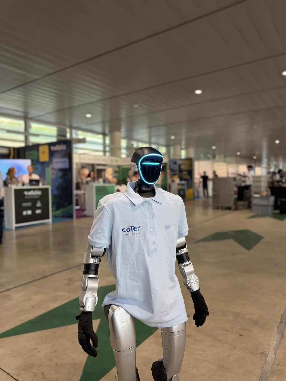 Robot humanoïde Unitree G1 en polo aux couleurs de l'organisateur, dans le hall d'exposition d'un congrès à Reims