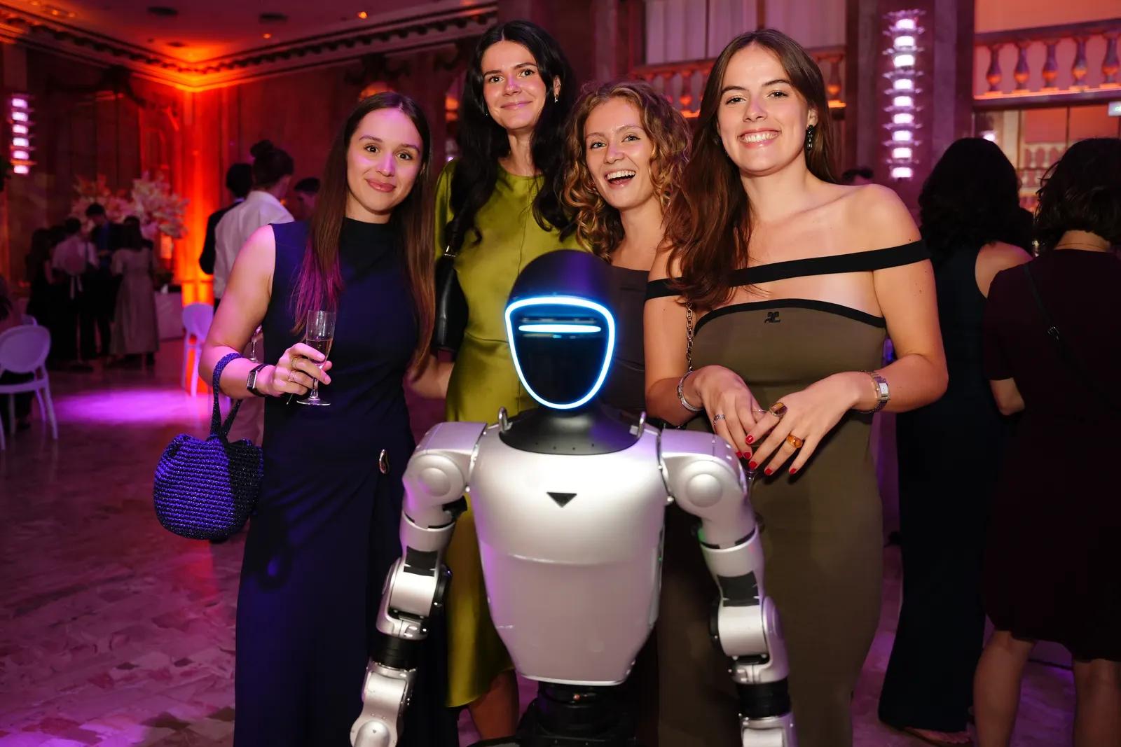 Le robot humanoïde Unitree G1 pose avec des invitées lors d'un gala étudiant à Paris