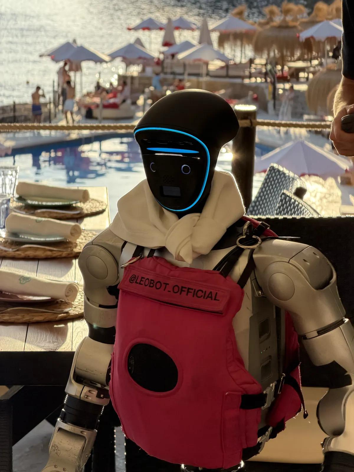 Robot humanoïde Unitree G1 assis à une table au bord de la piscine d'un beach club de Majorque